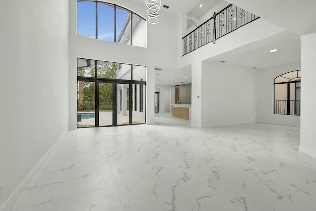 unfurnished living room featuring recessed lighting, marble finish floor, a notable chandelier, and baseboards