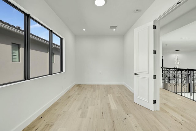 empty room featuring light wood-style floors, recessed lighting, visible vents, and baseboards