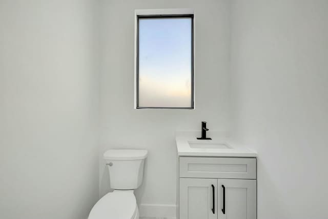 bathroom with baseboards, vanity, and toilet