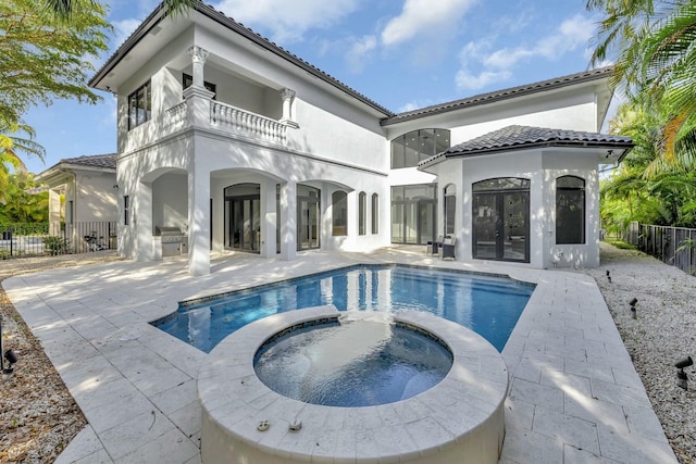 back of property featuring a patio, a balcony, a tiled roof, fence, and stucco siding