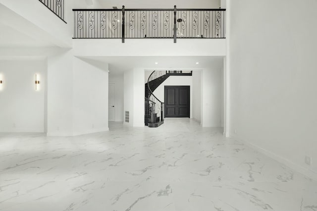 interior space with marble finish floor, baseboards, a high ceiling, and stairway