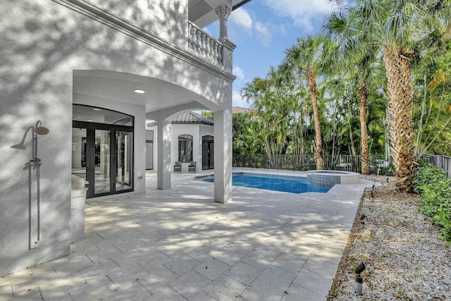 view of pool featuring a pool with connected hot tub, fence, a patio, and french doors