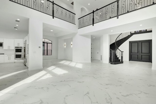 unfurnished living room featuring visible vents, a towering ceiling, stairway, marble finish floor, and recessed lighting