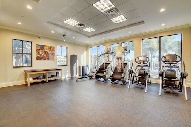 gym featuring a tray ceiling, crown molding, baseboards, and recessed lighting