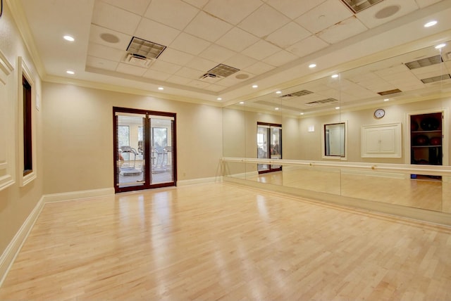 exercise area with ornamental molding, french doors, a tray ceiling, and light wood-type flooring