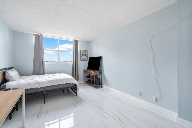 bedroom with a textured ceiling, marble finish floor, and baseboards