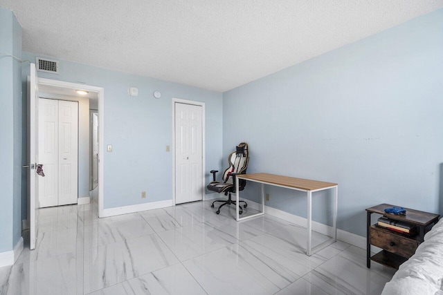 office area featuring a textured ceiling, marble finish floor, visible vents, and baseboards