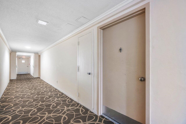 hall featuring ornamental molding, dark carpet, and a textured ceiling