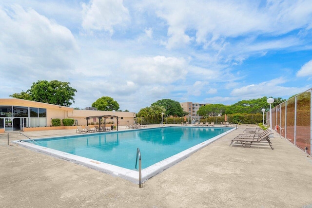 community pool with a patio area and fence