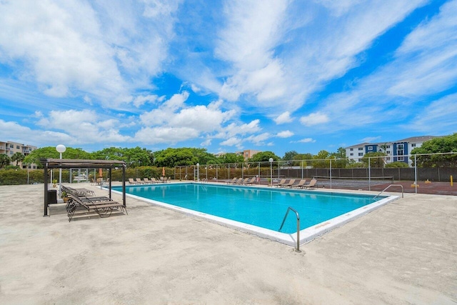 community pool with a patio area and fence