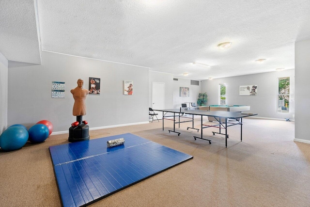 recreation room with light carpet, baseboards, and a textured ceiling