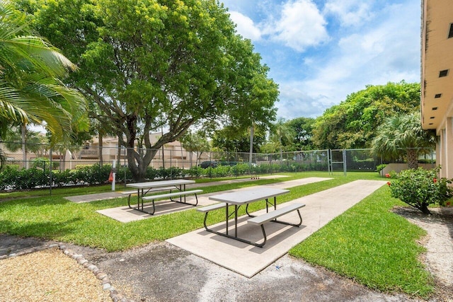 view of property's community featuring a lawn and fence