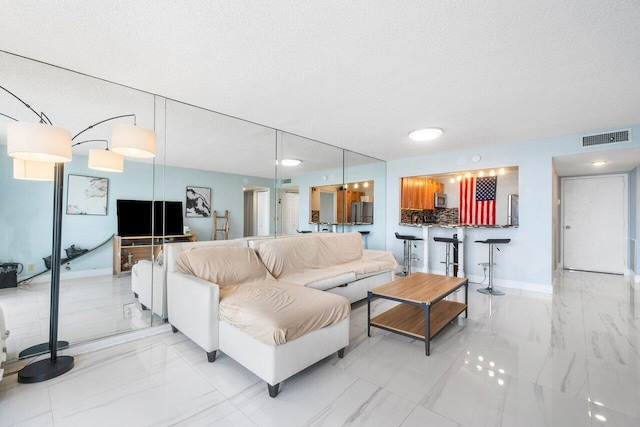 living room featuring marble finish floor, visible vents, and a textured ceiling