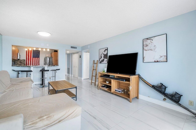 living area with baseboards, visible vents, and a textured ceiling