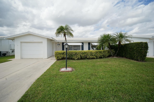 single story home featuring driveway, a front lawn, an attached garage, and stucco siding