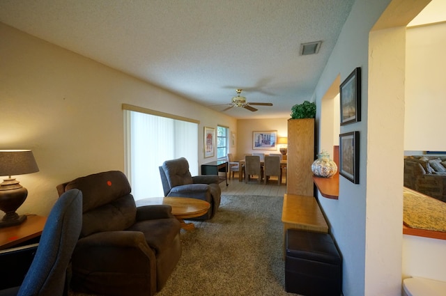 carpeted living room featuring ceiling fan, visible vents, and a textured ceiling