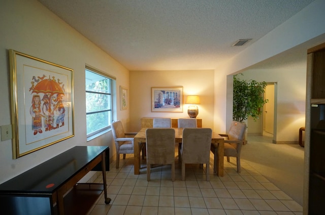 dining room featuring light tile patterned floors, visible vents, and a textured ceiling