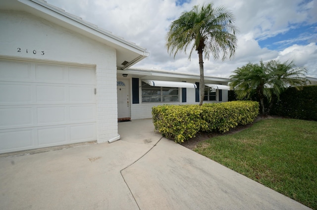 view of front of home featuring an attached garage, concrete block siding, and a front lawn