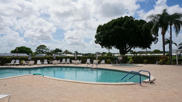 community pool featuring a patio area, fence, and a community hot tub