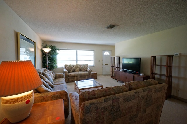 living area with light carpet, a textured ceiling, and visible vents