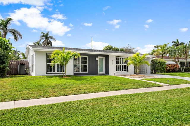 single story home featuring cooling unit, fence, driveway, stucco siding, and a front yard