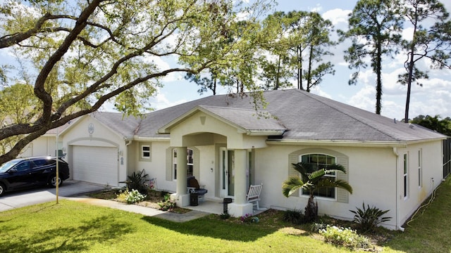 single story home featuring a front yard, a garage, driveway, and stucco siding