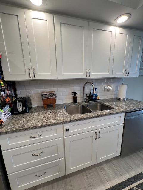 kitchen featuring white cabinets, dishwasher, and a sink