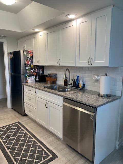 kitchen featuring appliances with stainless steel finishes, a sink, white cabinetry, and light wood-style floors