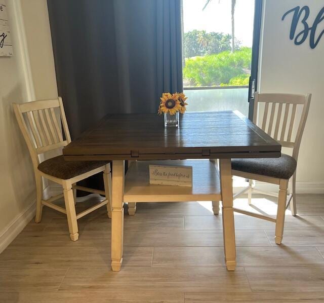 dining area with baseboards and wood finished floors