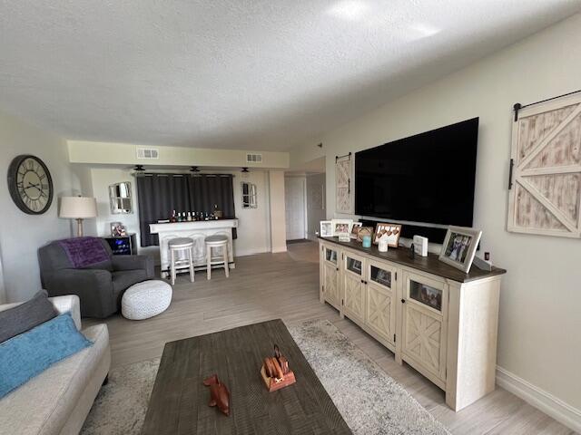 living area with visible vents, a textured ceiling, and light wood finished floors