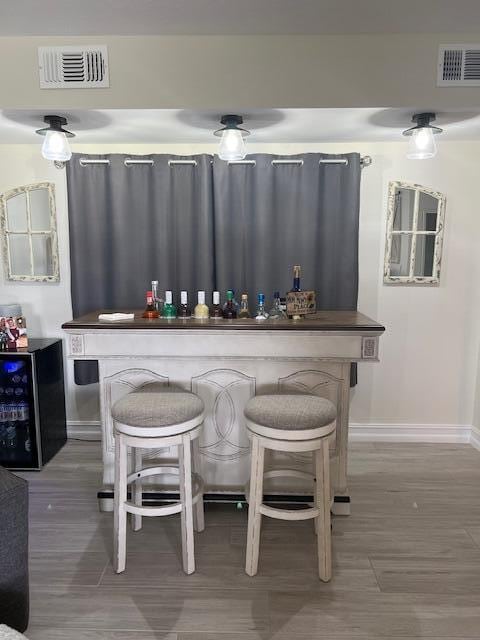 bar with wine cooler, visible vents, a dry bar, and baseboards