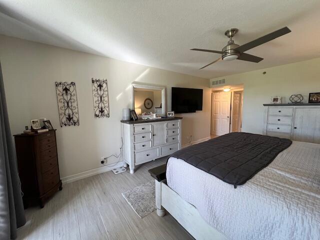 bedroom with ceiling fan, visible vents, light wood-style flooring, and baseboards