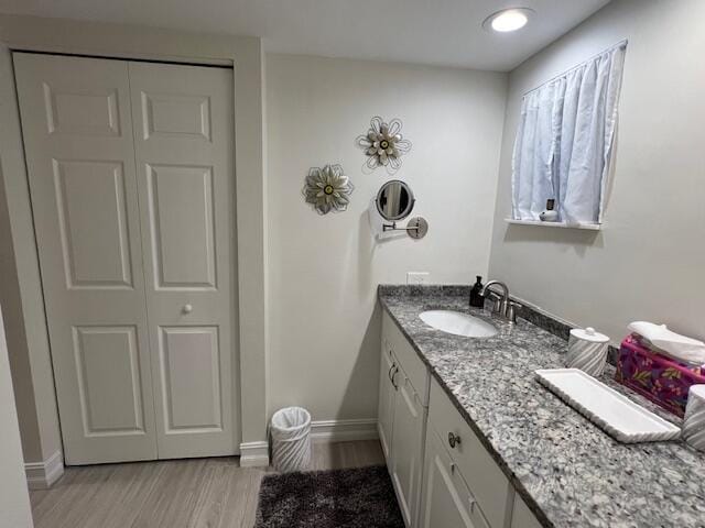 bathroom with vanity, baseboards, a closet, and wood finished floors