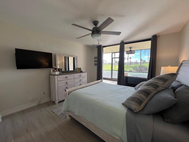 bedroom with light wood finished floors, baseboards, ceiling fan, access to exterior, and a wall of windows