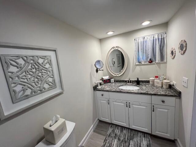 bathroom featuring recessed lighting, toilet, vanity, wood finished floors, and baseboards