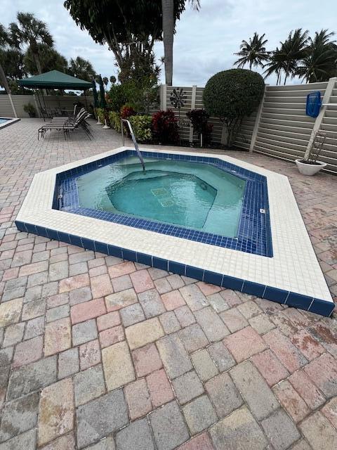 view of pool featuring outdoor dining area, a patio area, fence, and a hot tub