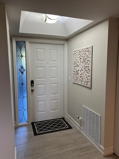 foyer entrance with light wood-style flooring, visible vents, and baseboards