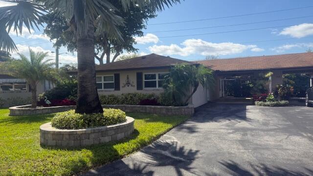 ranch-style house featuring concrete driveway and a front yard