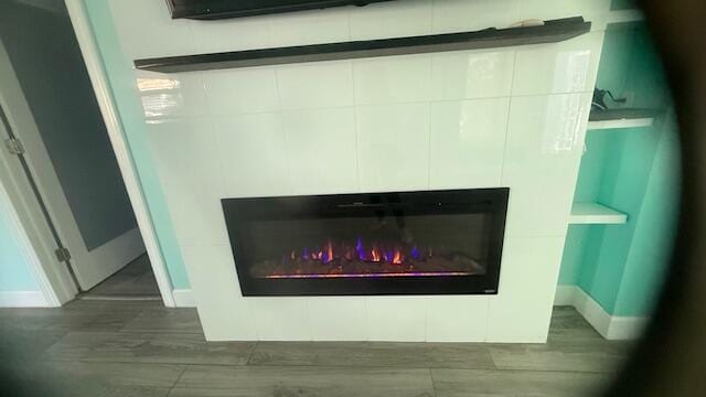 details with baseboards, wood finished floors, and a tile fireplace