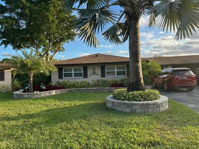 single story home featuring a front yard, driveway, and stucco siding