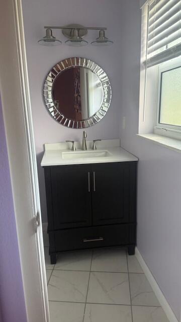 bathroom featuring marble finish floor, vanity, and baseboards