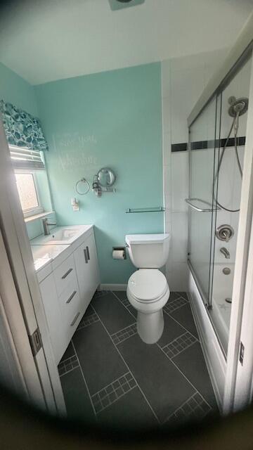 bathroom featuring toilet, vanity, and enclosed tub / shower combo