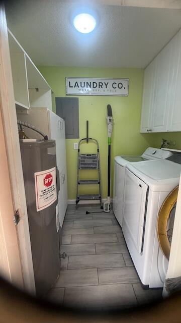 washroom with washing machine and clothes dryer, cabinet space, water heater, wood tiled floor, and electric panel