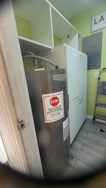 utility room featuring electric panel and water heater