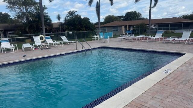 pool with a patio area and fence