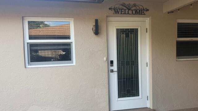 doorway to property featuring stucco siding