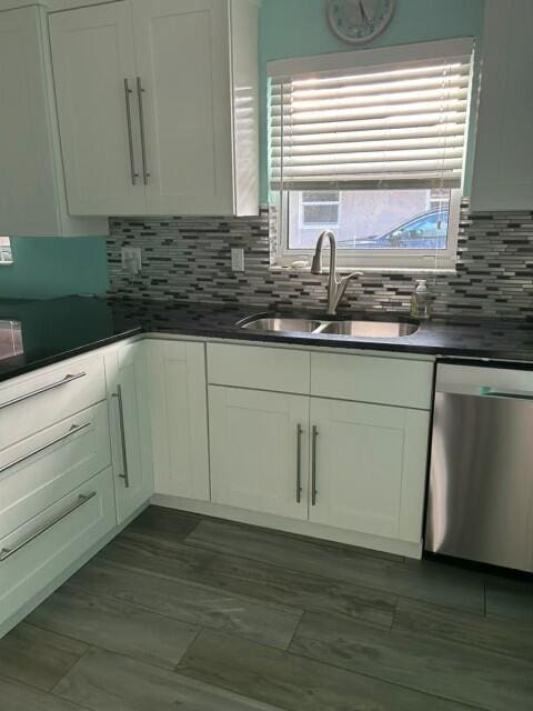 kitchen featuring a sink, dark countertops, decorative backsplash, and stainless steel dishwasher