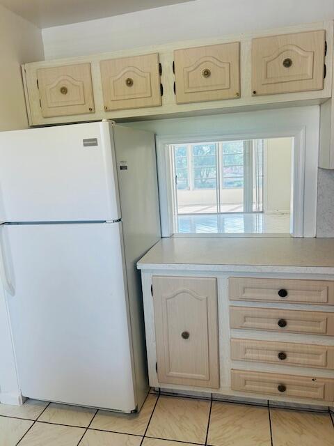 kitchen featuring light brown cabinetry, light countertops, and freestanding refrigerator