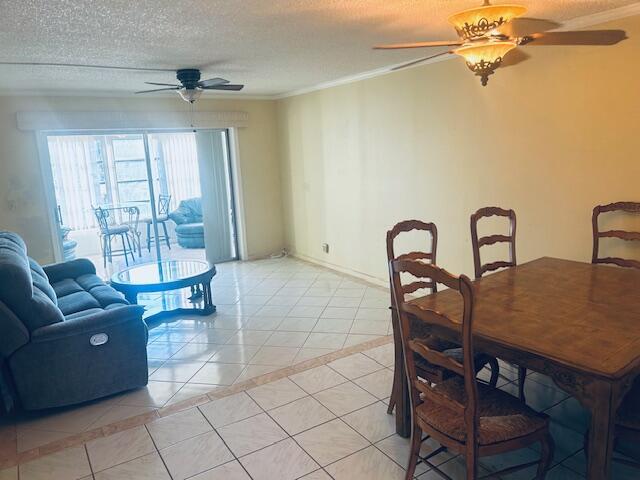 dining area with light tile patterned floors, ornamental molding, a textured ceiling, and a ceiling fan