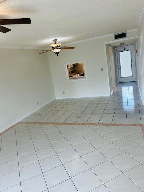 spare room with a ceiling fan, visible vents, and crown molding